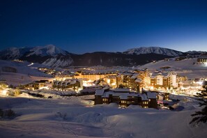 A snow-covered mountain town at night with illuminated buildings and ski slopes in the background. - Nordic Inn (Crested Butte)
