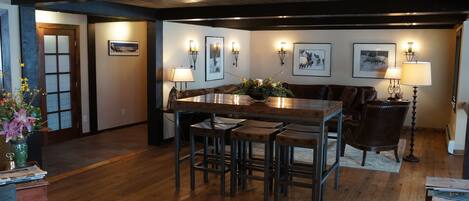 A dining area with a wooden table, four barstools, a bench, and wall-mounted lamps.