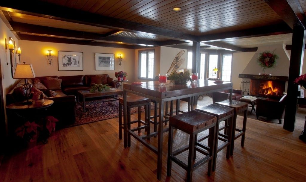 A cozy living room with wooden floors, a fireplace, and a bar area with stools.