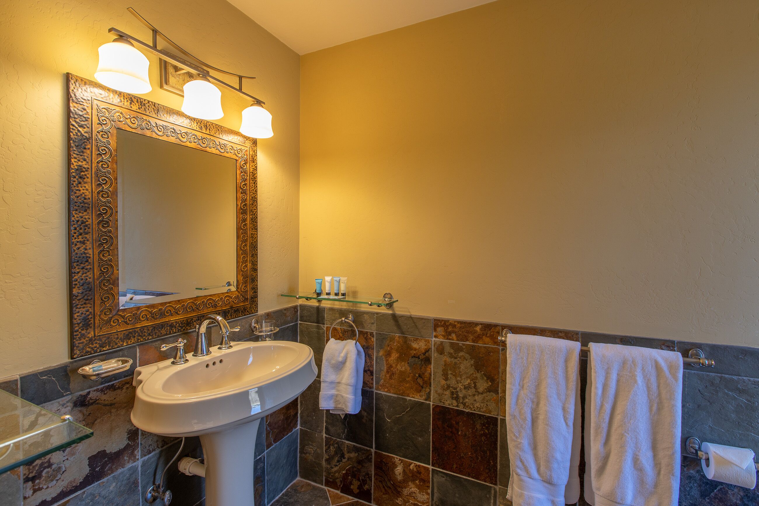 A bathroom with a large mirror, a sink, and two towels hanging on the wall.