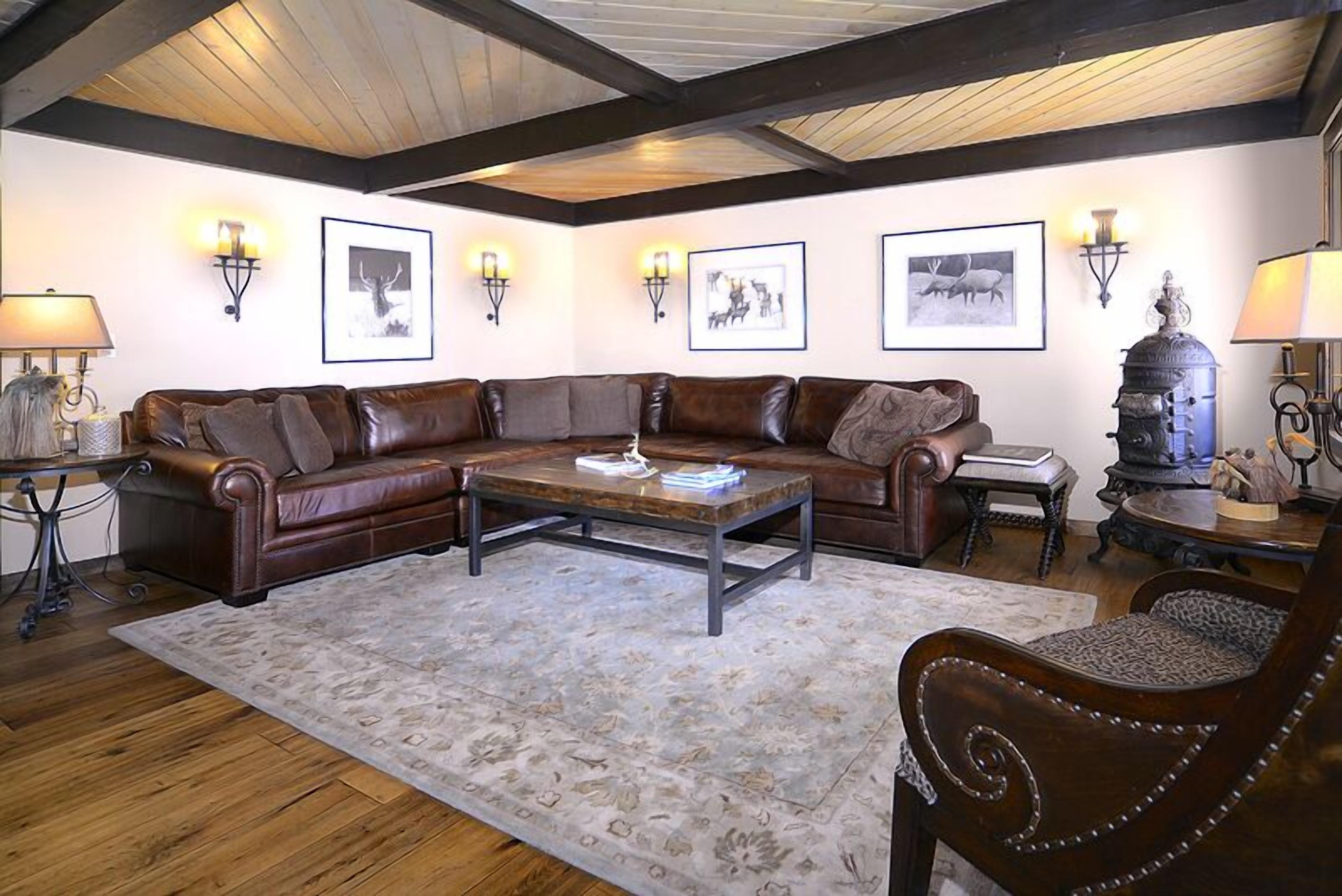 A cozy living room with a leather sectional sofa, a wooden coffee table, and a fireplace.