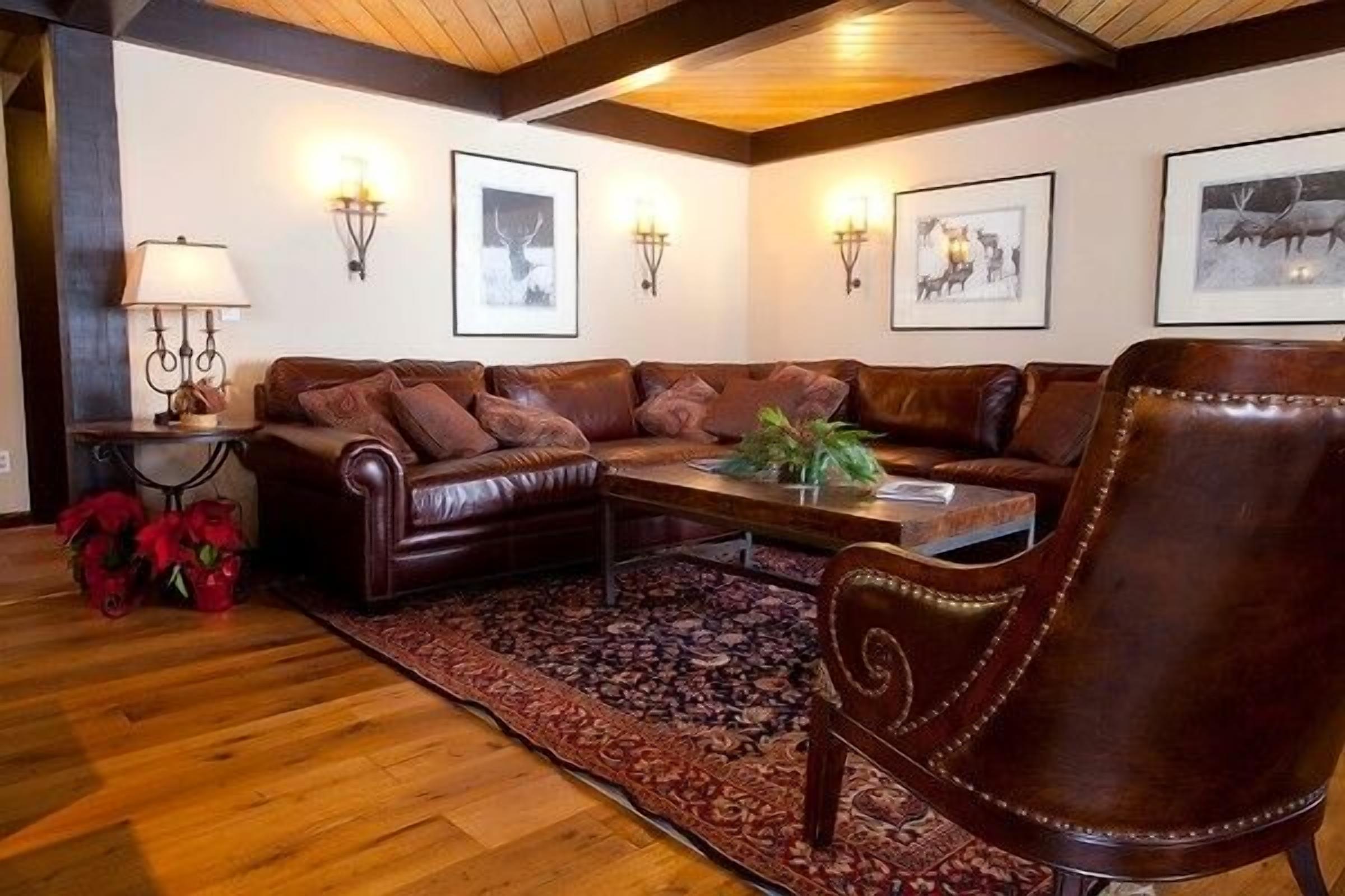 A cozy living room with a leather sofa, a wooden coffee table, and a patterned rug.
