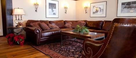 A cozy living room with a leather sofa, a wooden coffee table, and a patterned rug.
