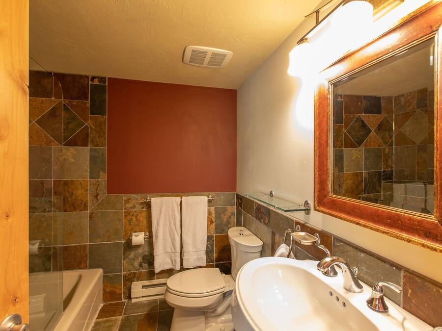 A bathroom with a bathtub, toilet, sink, and a large mirror.