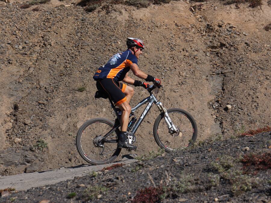 Uma pessoa andando de bicicleta de montanha em um caminho de terra.