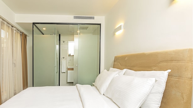 A hotel room with a bed, a headboard, and a glass door leading to a bathroom. - Septimum (Istanbul)