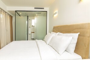 A hotel room with a bed, a headboard, and a glass door leading to a bathroom. - Septimum (Istanbul)