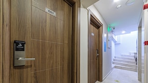 A hallway with wooden doors, a digital lock, and a staircase leading to an upper floor. - Septimum (Istanbul)