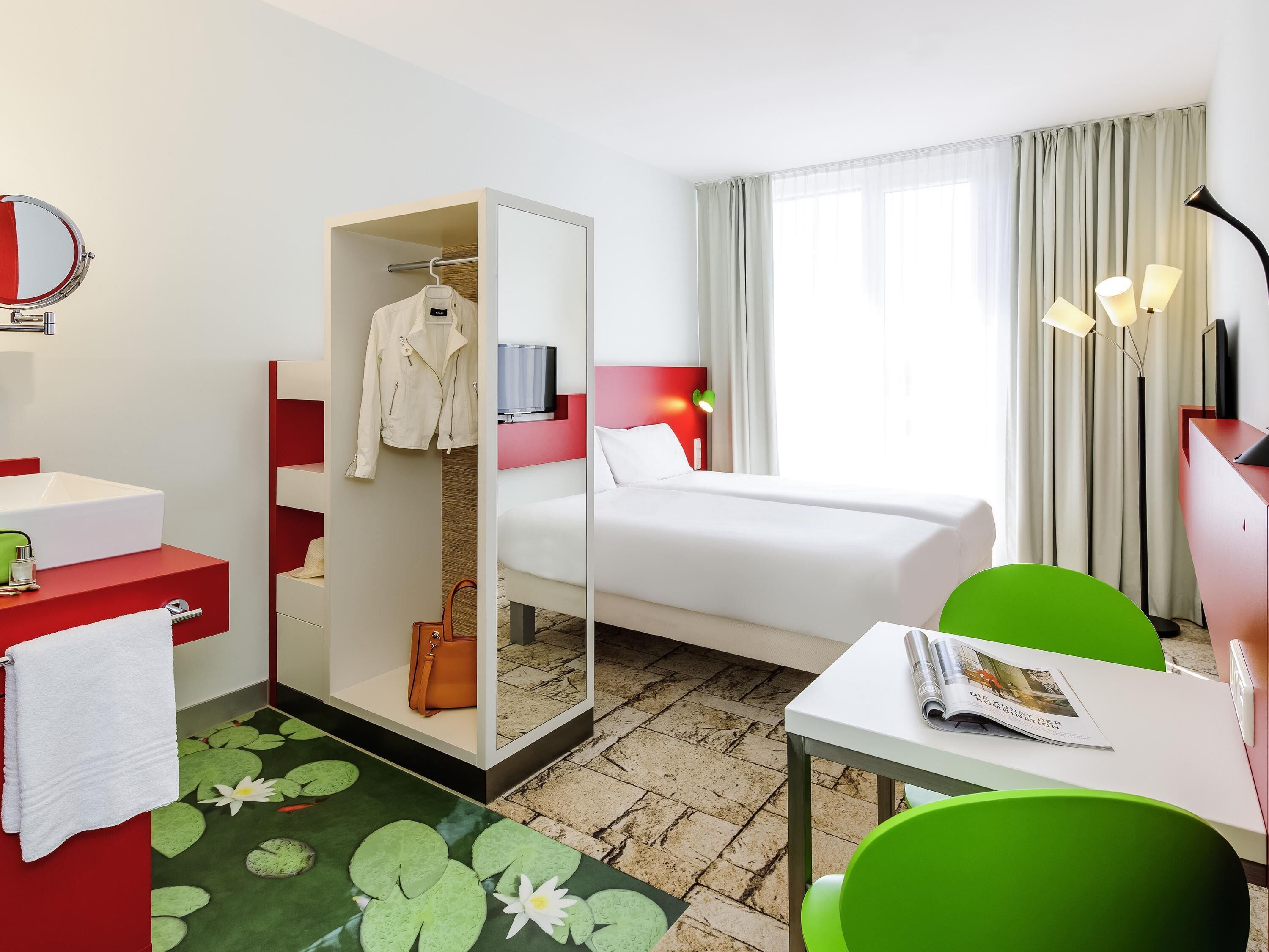 Une chambre d’hôtel comprenant un lit, un bureau, une chaise, une armoire, un miroir et une salle de bain.