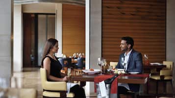 A couple dining at a restaurant with a modern interior, featuring wooden paneling and a spacious layout.