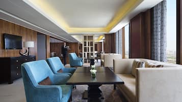Una habitación de hotel moderna con un ventanal grande, un televisor de pantalla plana, una mesa de comedor y un sofá.