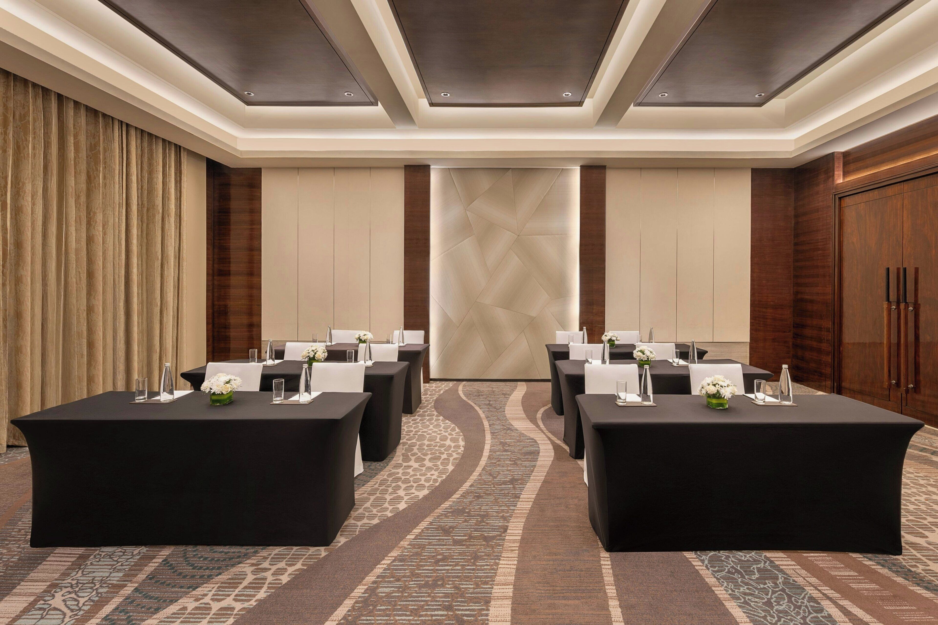 A conference room with a long table, chairs, and a decorative wall panel.