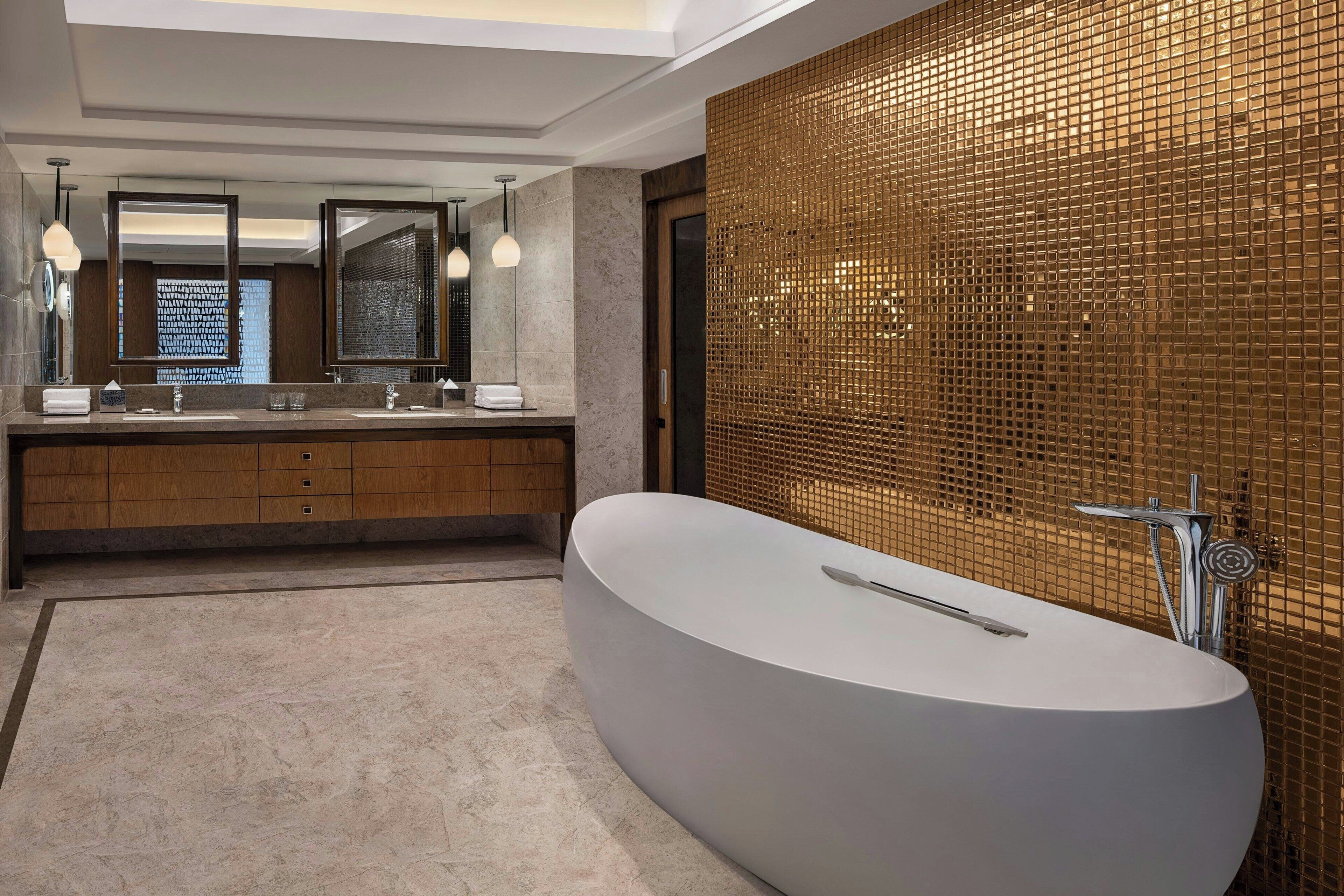 Un baño moderno con un lavamanos ovalado grande, lavamanos dobles y un espejo amplio.