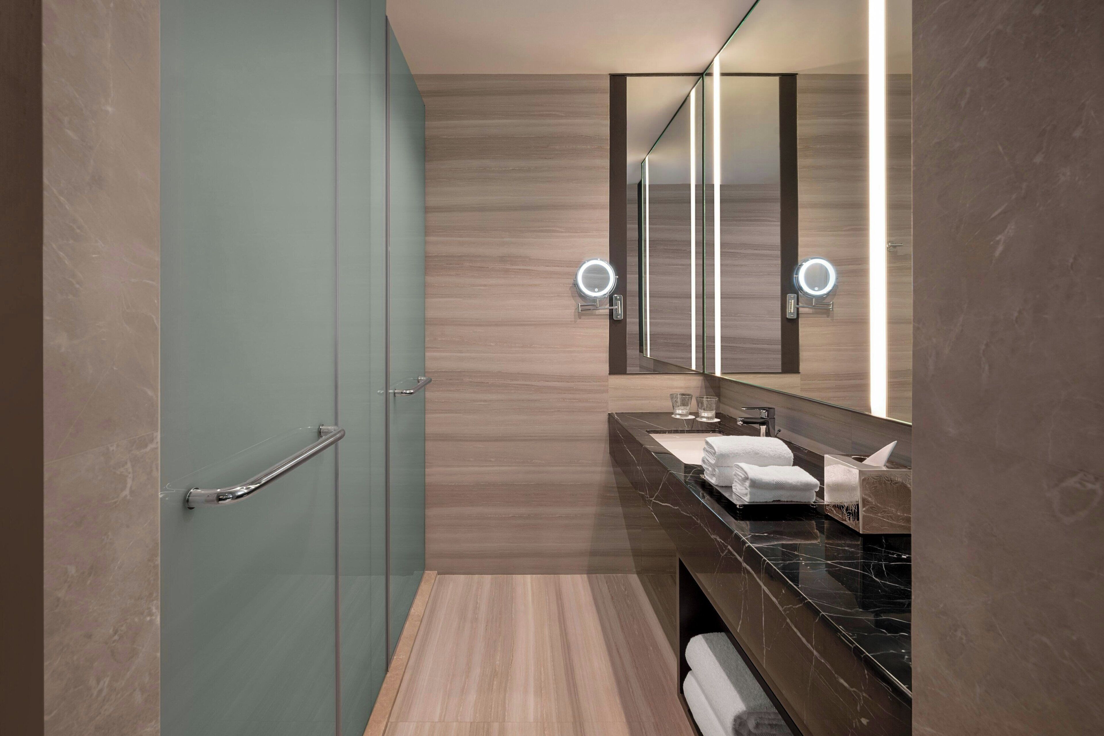 Un baño moderno con tocador, espejo con luces y barandilla.