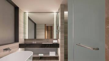 A modern bathroom with a freestanding bathtub, a vanity with a marble countertop, and a large mirror.