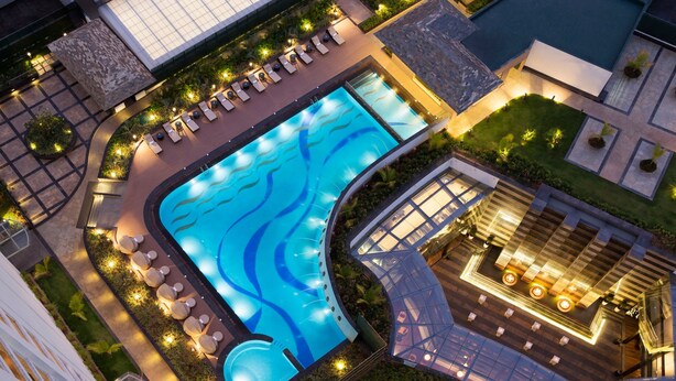 Vista aérea de un hotel con una piscina grande, tumbonas y un área exterior bien iluminada.