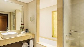 A modern bathroom with a large mirror, a sink, a glass shower enclosure, and a bathtub.