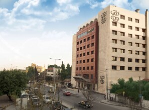 A hotel with a modern facade, multiple floors, and a prominent logo on the side.
