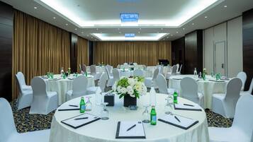 A conference room with round tables, white chairs, and floral centerpieces.
