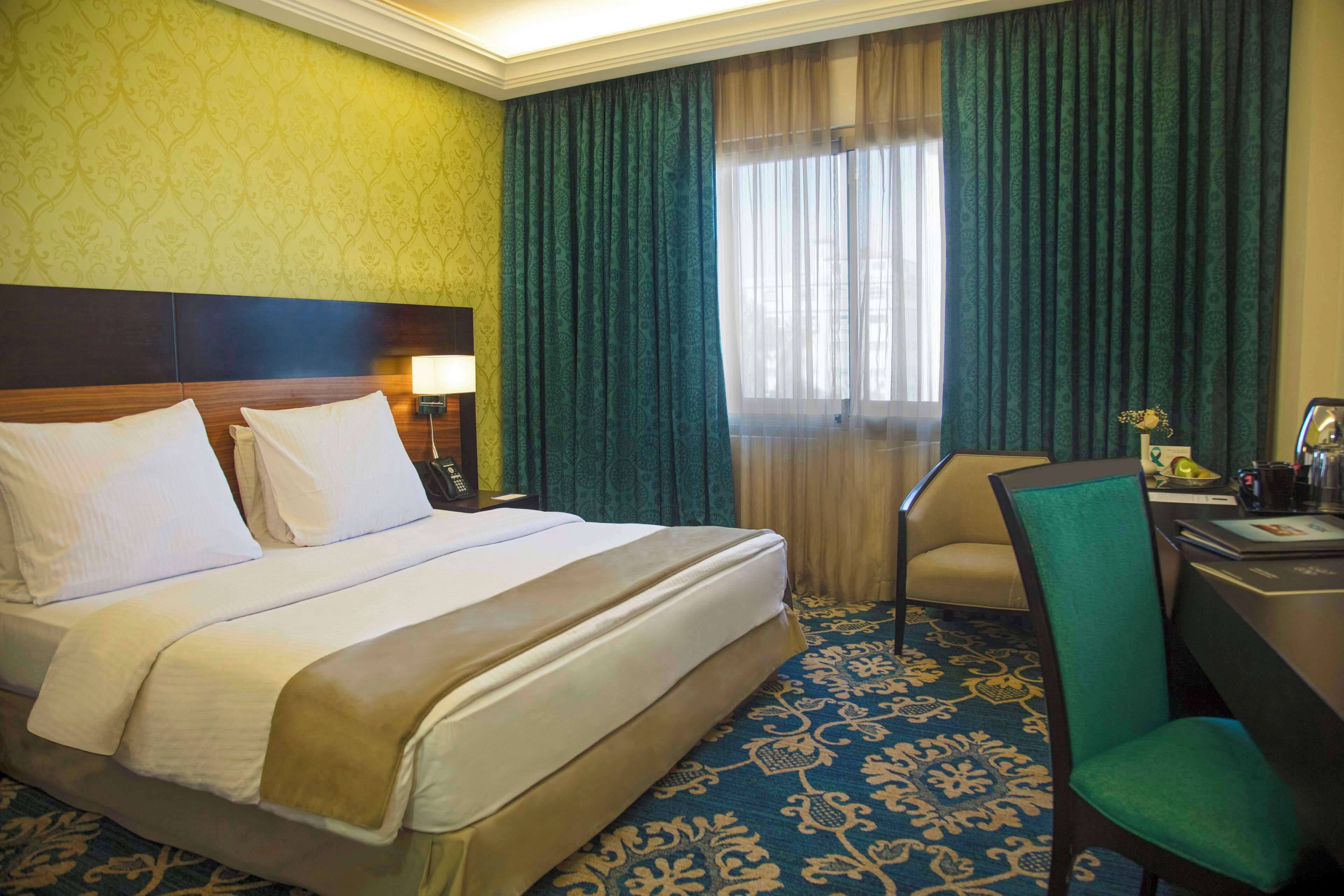 Een hotelkamer met een groot bed, een bureau en een stoel.