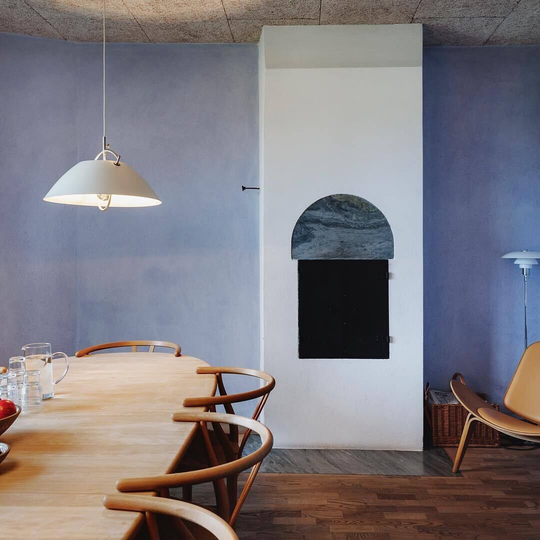 A dining area with a wooden table, chairs, and hanging pendant lights.