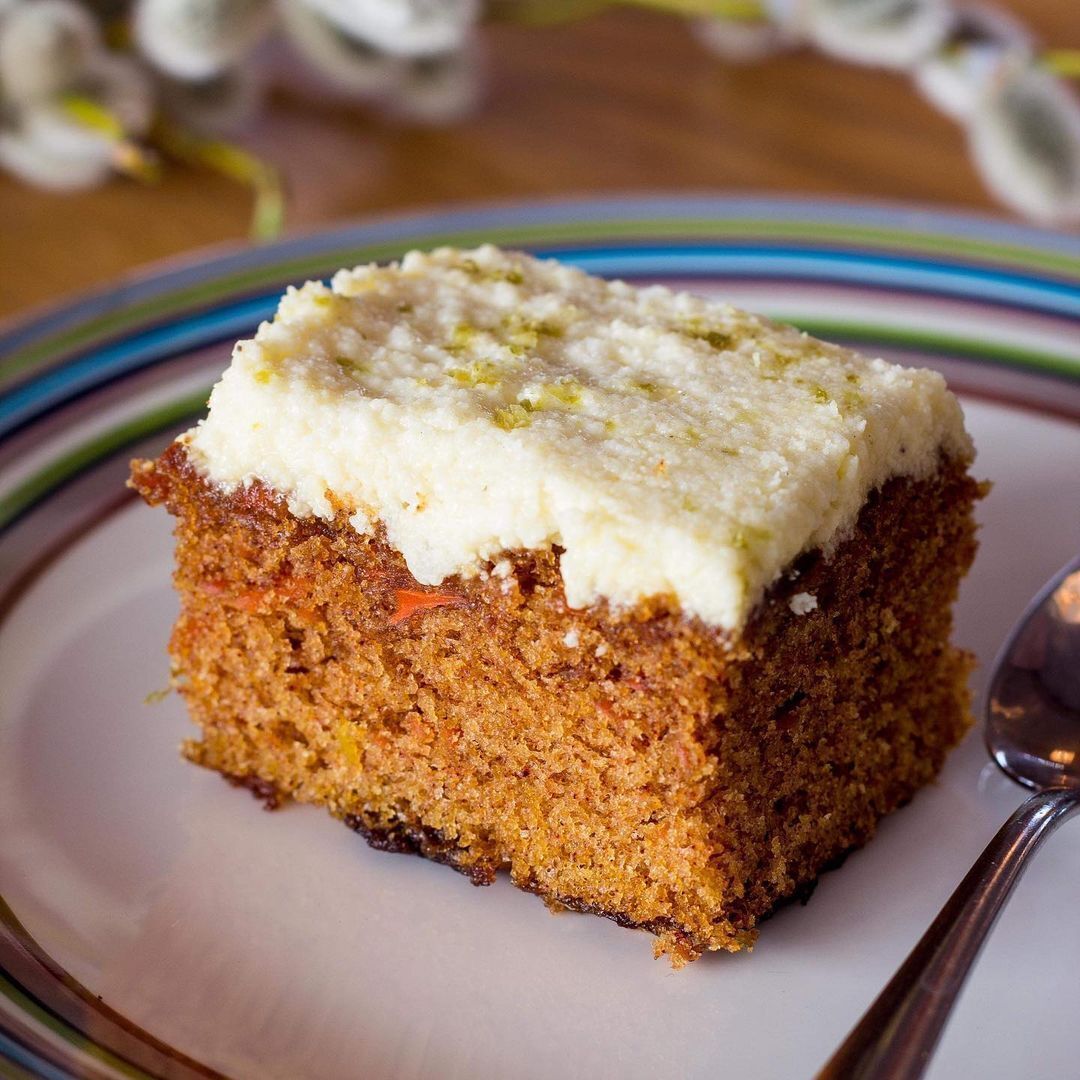 A slice of carrot cake with cream cheese frosting on a plate.