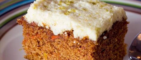 A slice of carrot cake with cream cheese frosting on a plate.