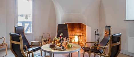 A cozy room with a fireplace, wooden chairs, a round table, and hanging light fixtures.