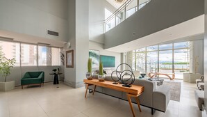 Un amplio salón con techo alto, ventanas grandes y vistas al exterior.
