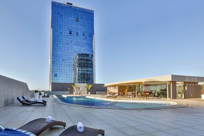 A rooftop pool area with lounge chairs, a pool, and a modern building in the background. - Nobile Suites Del Rio - Petrolina (Petrolina)