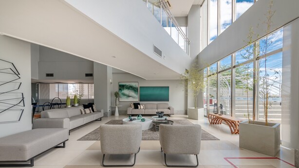 Un salón amplio con un sofá moderno, una mesa de centro y dos sillones. Hay un ventanal que ofrece vistas al exterior.