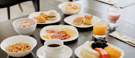 A breakfast table with various dishes, including cereal, pastries, and fruit.