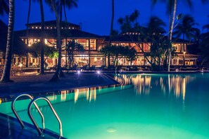 Relax by the pool surrounded by palm trees and enjoy the resort's lounge area with seating.