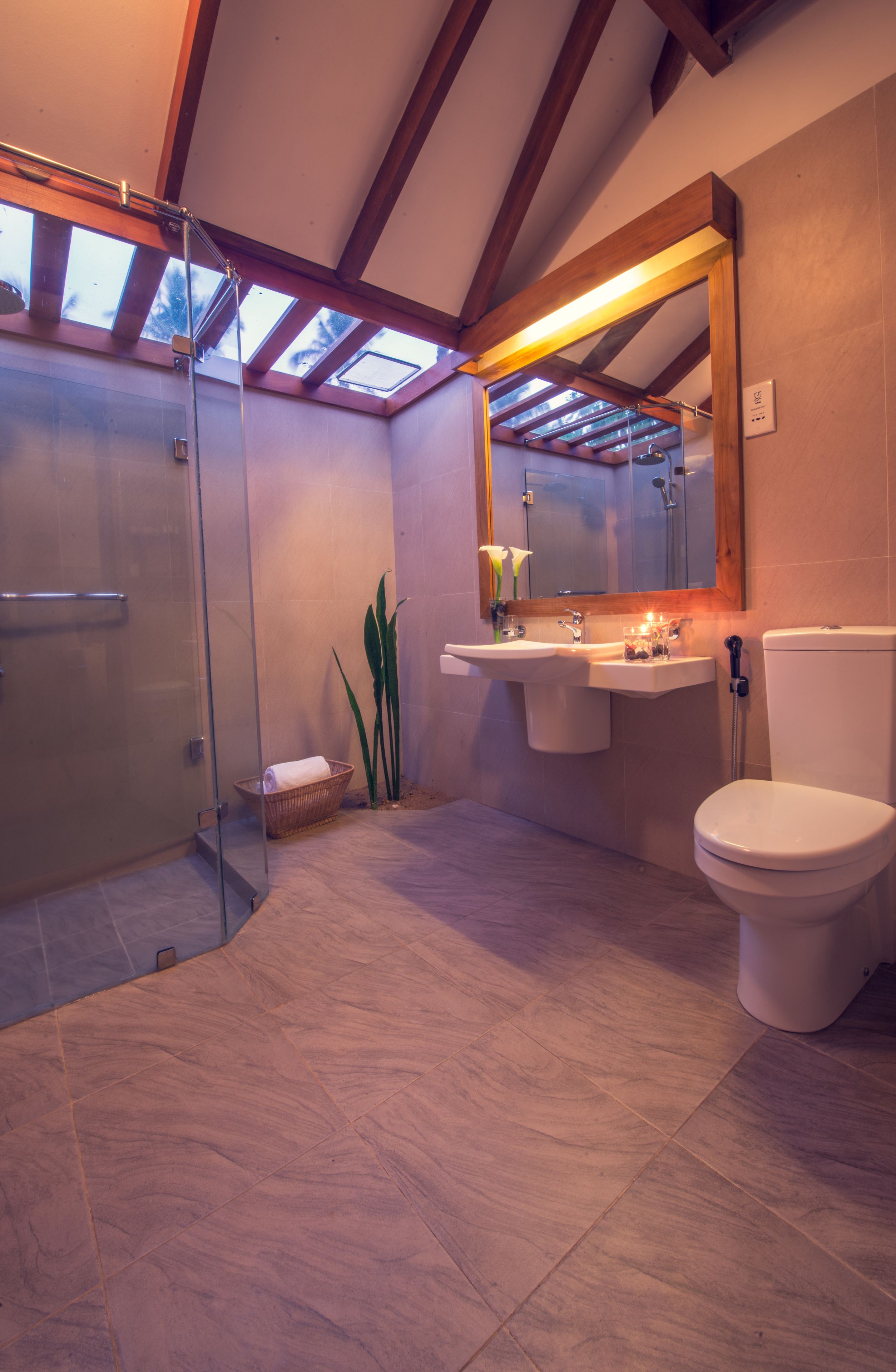 A modern bathroom with a glass shower enclosure, a sink with a mirror, and a toilet.