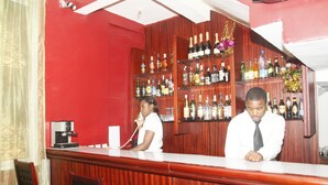 Eine Bar mit Holzwandverkleidung, einer Theke und Regalen voller Flaschen.