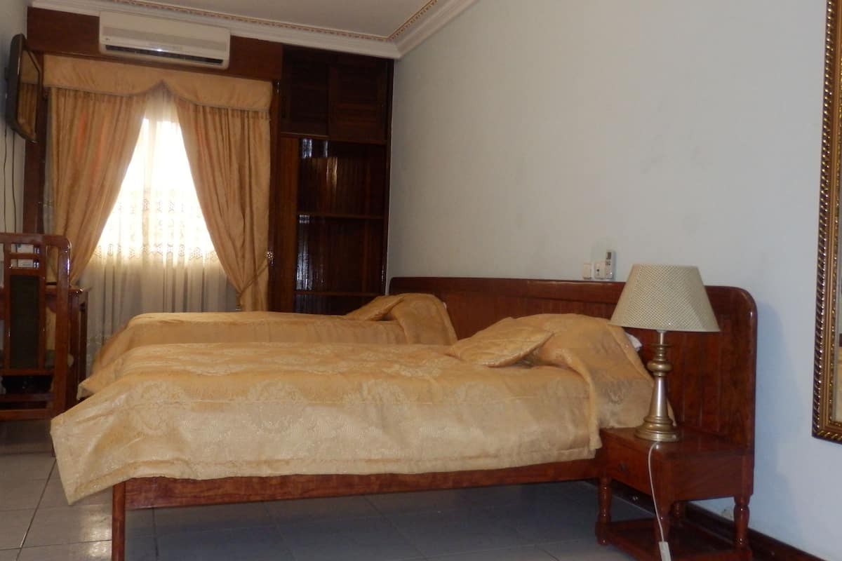 Une chambre à coucher avec un grand lit, une table de chevet en bois avec une lampe, un miroir, une armoire et une chaise.
