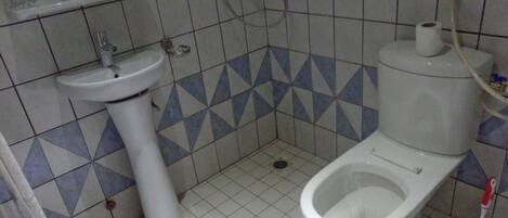 A small bathroom with a toilet, sink, and shower.