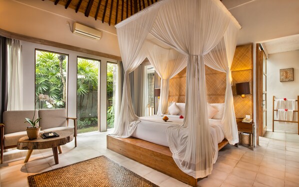 A spacious bedroom with a canopy bed, large windows, and a view of greenery.