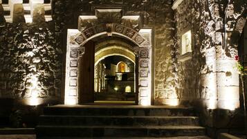 A stone archway leading to a building entrance with steps and a small window above the door.