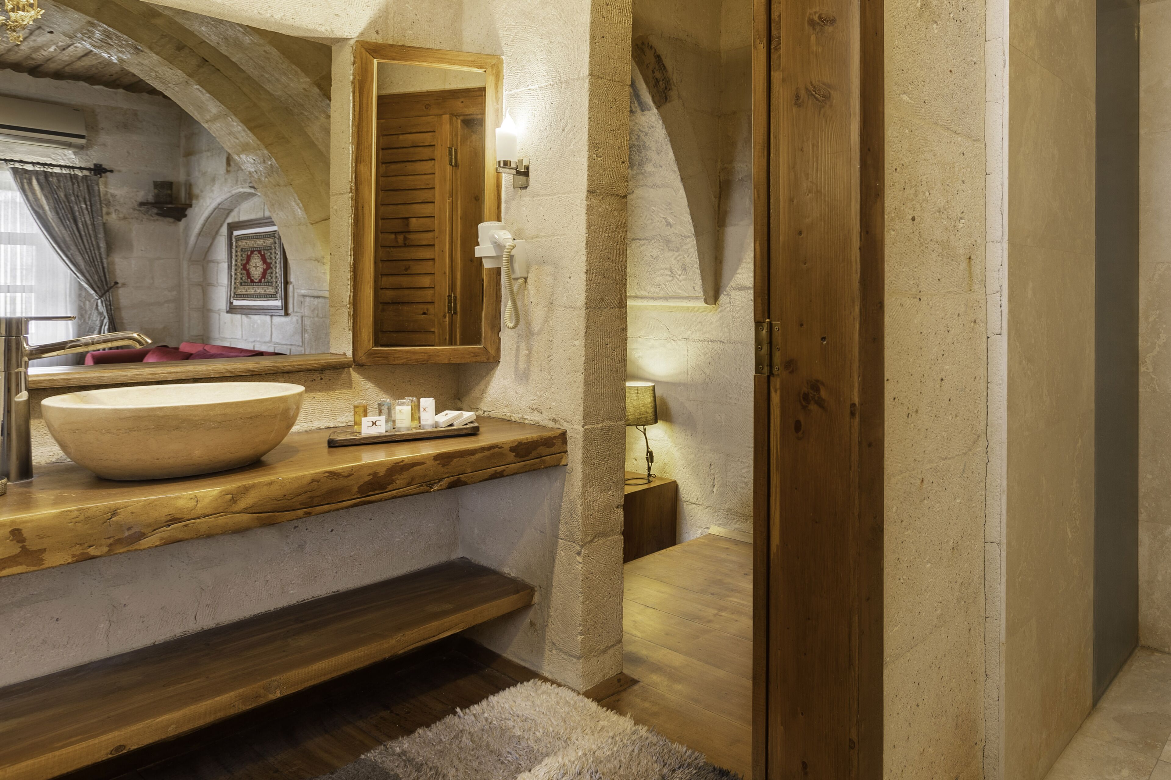 Un baño rústico con un lavabo de piedra grande, tocador de madera y techo abovedado.