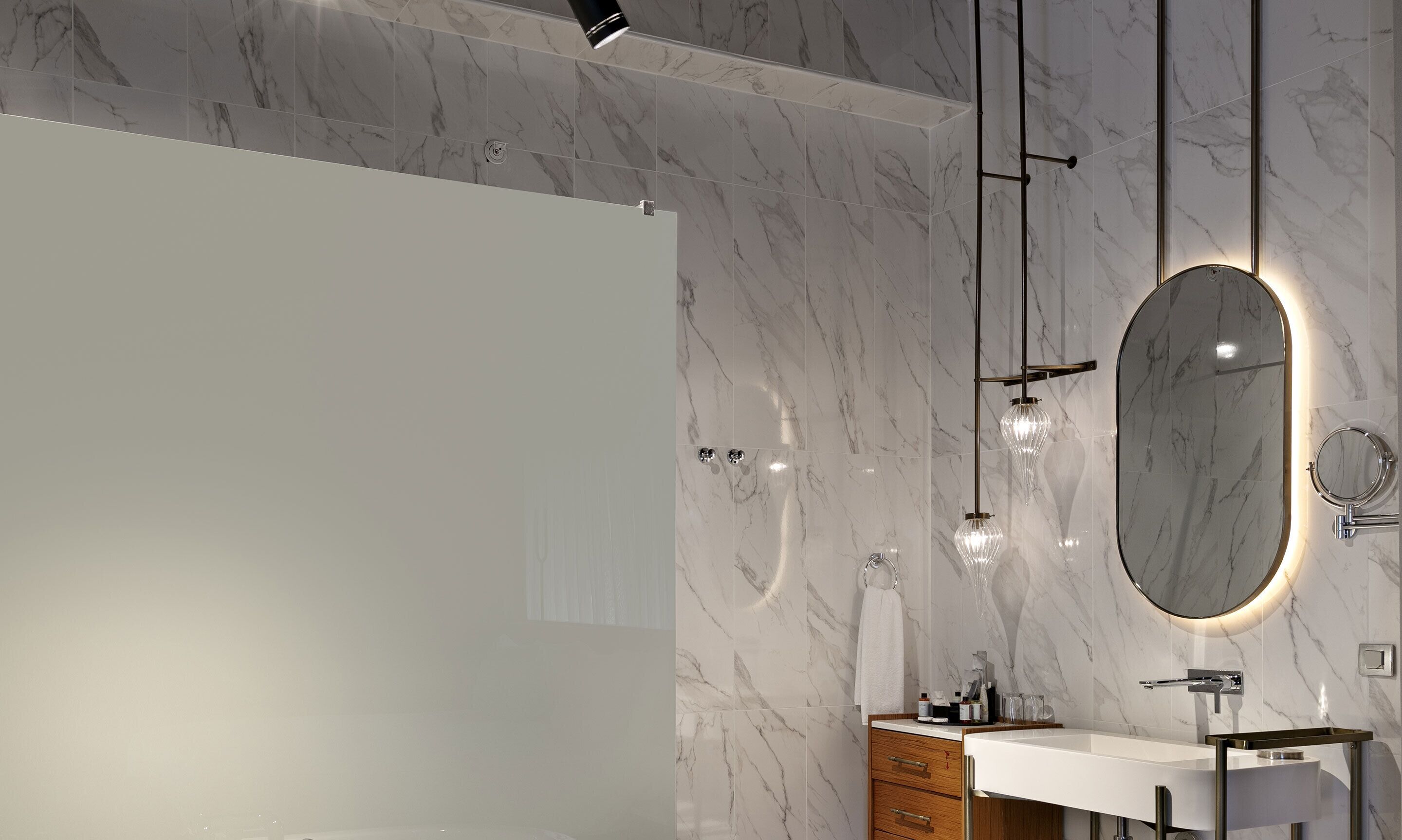 A modern bathroom with a marble backsplash, a freestanding mirror, and pendant lights.