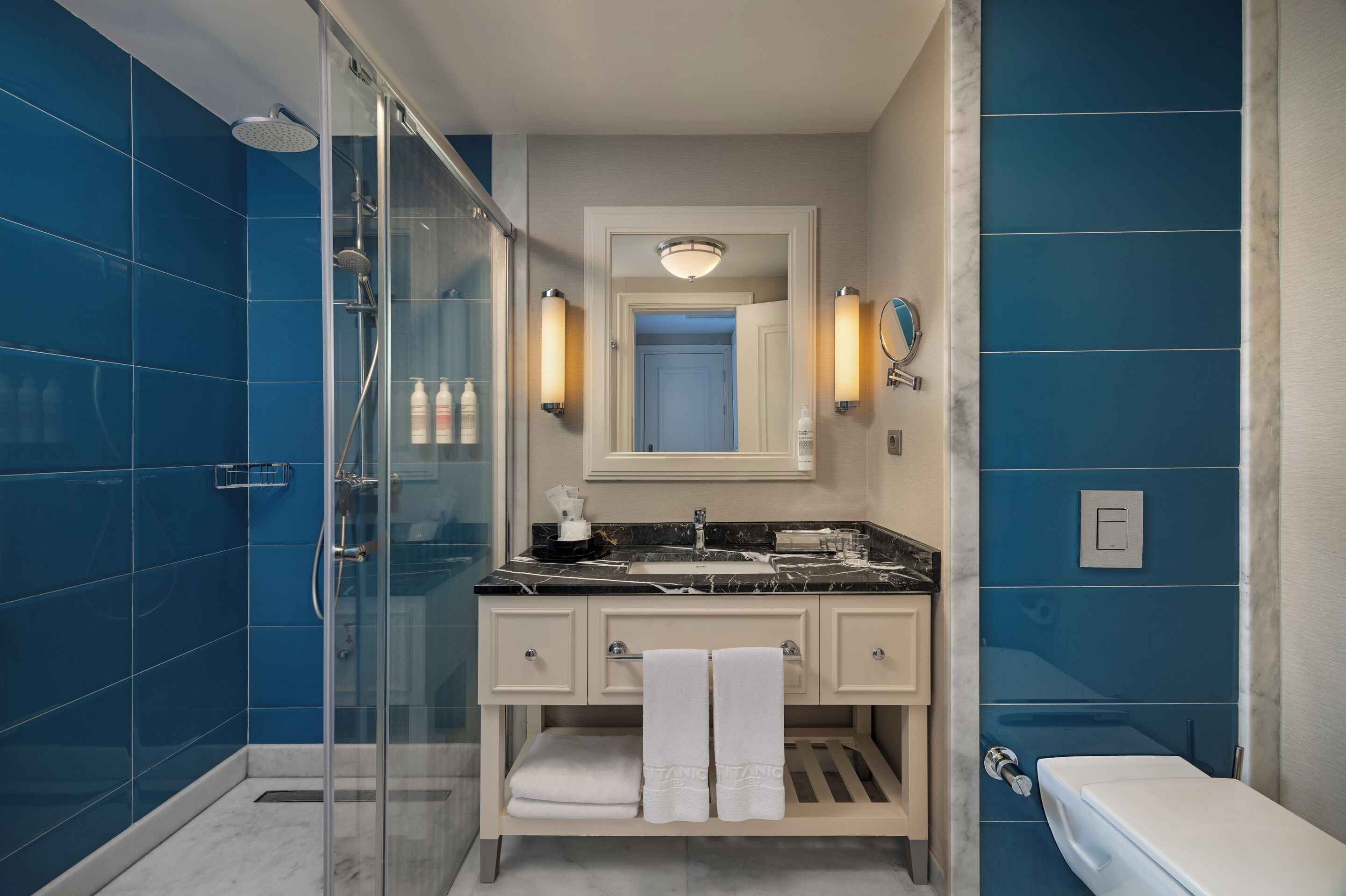Un baño moderno con ducha de vidrio, lavamanos de mármol y un inodoro.