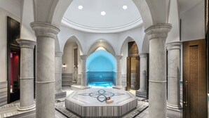 A grand lobby with marble columns, a central fountain, and a high ceiling.