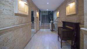 A hallway with stone walls, a wooden bench, and a staircase leading to an upper level. - Casual de las Civilizaciones Valencia by Casual Hoteles (Valencia)