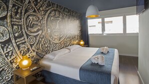 A hotel room with a bed, a tapestry with intricate designs, a window with a view, and a wall-mounted TV. - Casual de las Civilizaciones Valencia by Casual Hoteles (Valencia)