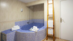 A bathroom with a blue-tiled bathtub, a wooden ladder, and a white door. - Casual de las Civilizaciones Valencia by Casual Hoteles (Valencia)