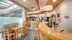 Un espace bar moderne, doté de mobilier en bois et d’un comptoir incurvé.