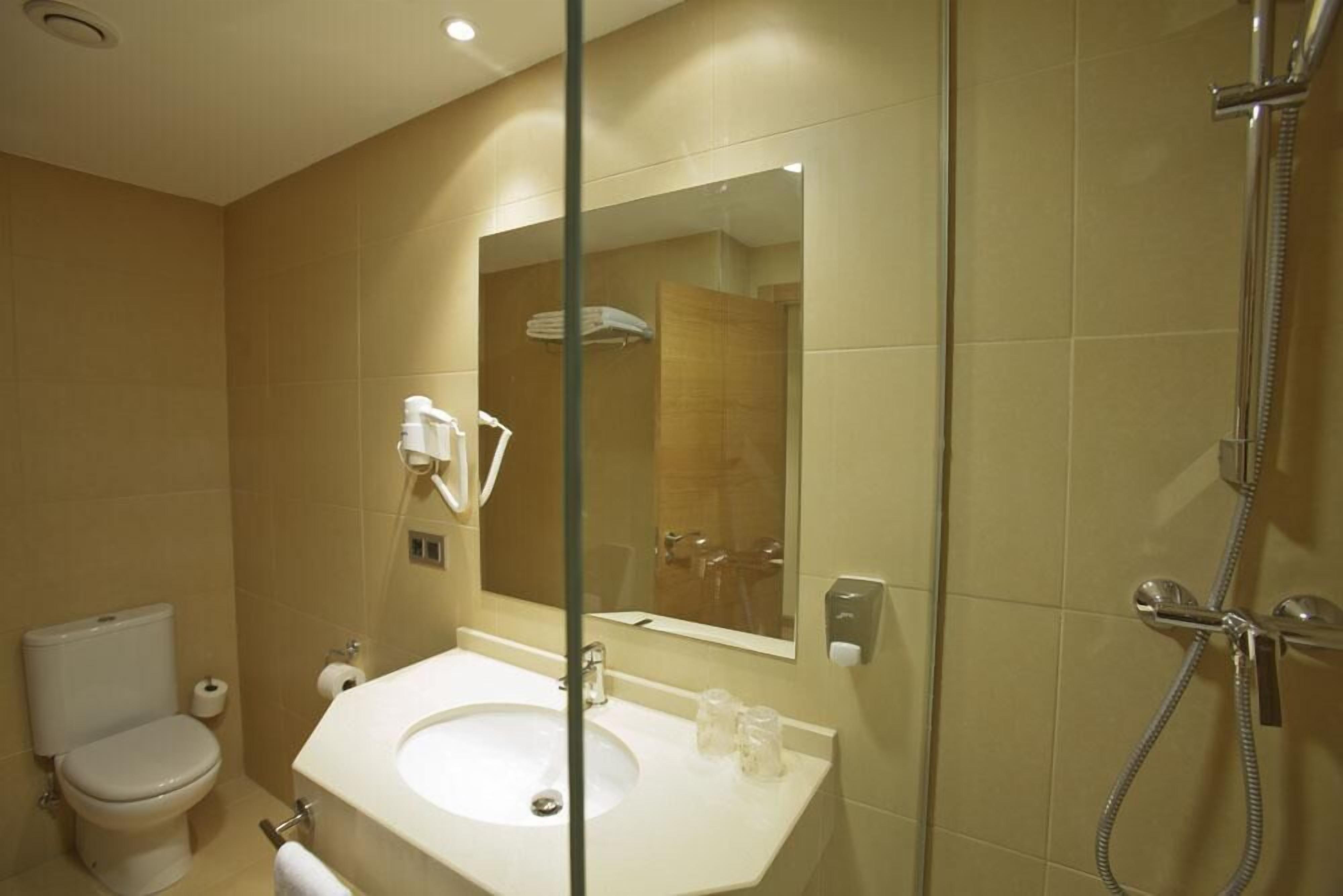 A modern bathroom with a toilet, sink, and shower.