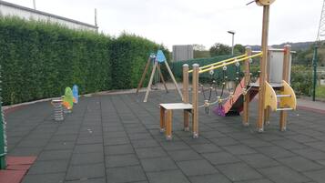 Kids can play on swings, a slide, and climbing structures in this outdoor playground.