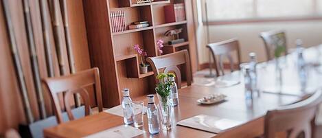 A wooden dining table with chairs, water bottles, and a vase with flowers.